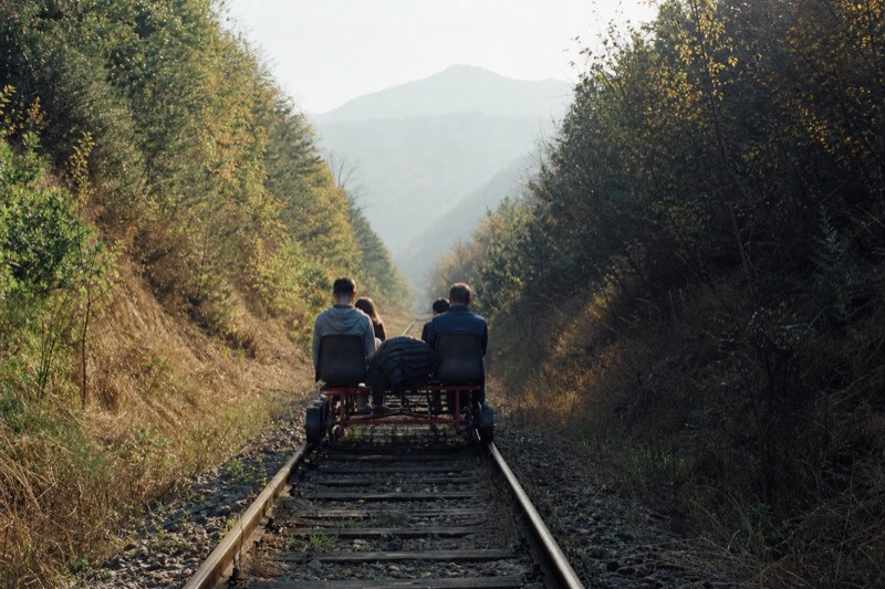 A four-seat rail bike on a disused railway track running beside a river between wooded Korean hillsides